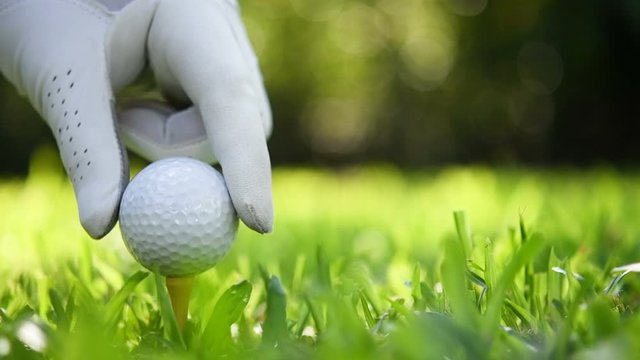 Hand putting golf ball on green grass , slow motion .
