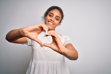Naklejka premium Young beautiful african american girl wearing casual t-shirt standing over white background smiling in love doing heart symbol shape with hands. Romantic concept.