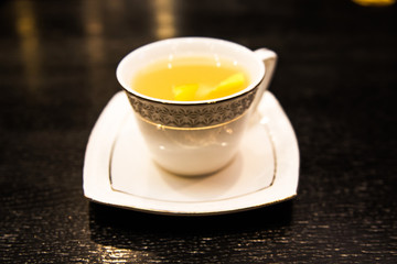 warming alcoholic cocktail in a white Cup on a dark background, the bar with a cinnamon stick and an orange orange