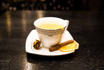 warming alcoholic cocktail in a white Cup on a dark background, the bar with a cinnamon stick and an orange orange