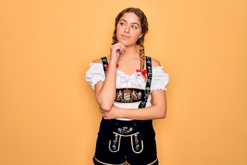 Young beautiful blonde german woman with blue eyes wearing traditional octoberfest dress with hand...