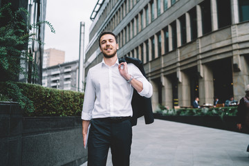 Elegant adult businessman in suit walking on pedestrian street