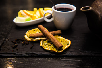 Mulled wine, sangria, mulled wine in a white Cup on a dark background, bar counter with fruit, tea and spices. Cinnamon sticks and orange
