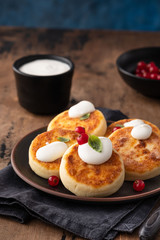 Cottage cheese pancakes Russian syrniki with red currant and yogurt, selective focus.