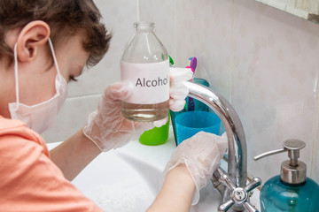A bottle of alcohol. A European boy wipes the faucet in the bathroom from germs, bacteria, viruses.