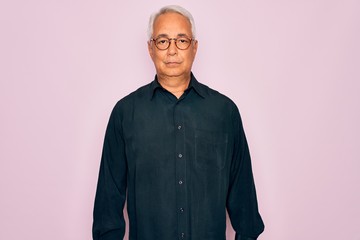 Middle age senior grey-haired handsome man wearing glasses and elegant shirt with serious expression on face. Simple and natural looking at the camera.