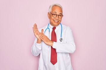 Middle age senior grey-haired doctor man wearing stethoscope and professional medical coat clapping...