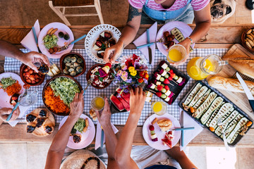 Top view of group of friends have fun together in an healthy fresh seasonal brunch together - coloured and energetic food to eat with friends or family - people stay ogether at home or restaurant