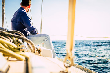 Man sit on a sail boat travel the ocean and enjoy freedom lifestyle - concept of sailing and having...