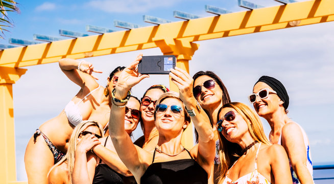 Group of happy and cheerful young caucasian women have fun together in friendship taking selfie picture during summer holiday vacation - females with bikini swimwear enjoying and laughing a lot