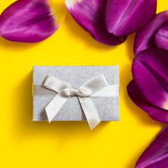 Holiday gift box and tulips on yellow background.