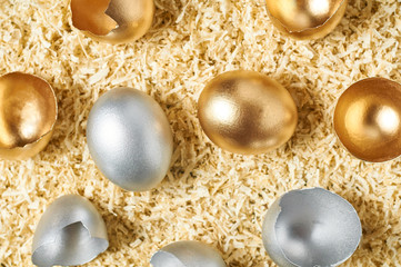 Golden and silver eggs, shells in nest. Concept of easter, pricelless ideas, successful business investment or luxury breakfast. Top view