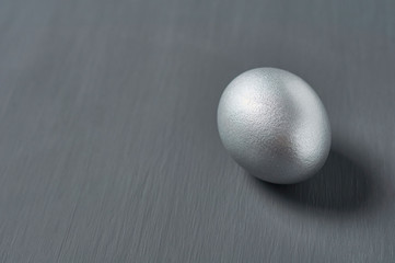 Silver egg on dark concrete background. Concept of easter, pricelless ideas, successful business investment or luxury breakfast. Copy space