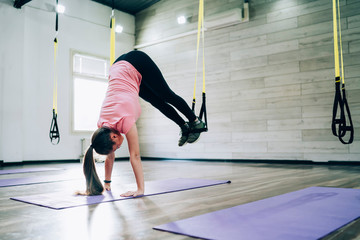 Young woman doing handstand with rubber expander