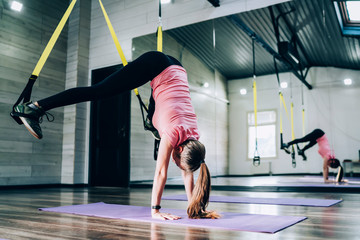Young sportswoman doing handstand in fitness studio