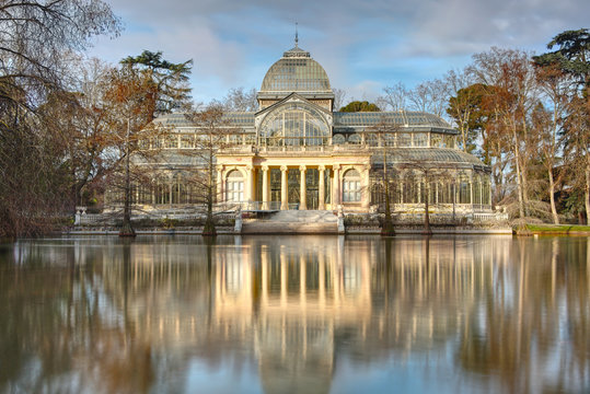 Glass Palace, the Crystal Palace in Retiro Park, Madrid, Spain. Historic glass pavilion and former greenhouse. Long exposure landscape view with pond, empty of people.