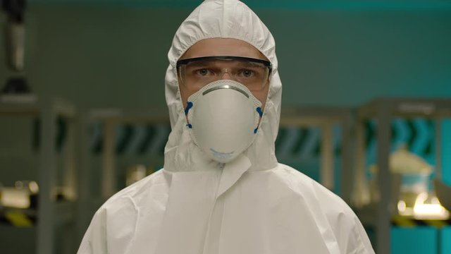 Portrait of the Professional Surgeon . In the background modern laboratory Operating Room . Pandemic, portrait of a young man doctor with coverall . Shot on ARRI ALEXA Cinema Camera in slow motion .