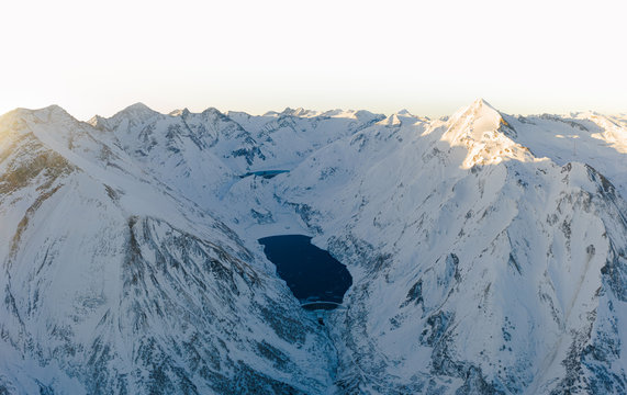 Luftaufnahme von Gebirgsstauseen im Morgengrauen mit Alpengl&uuml;hen in Winterlandschaft in den Alpen 