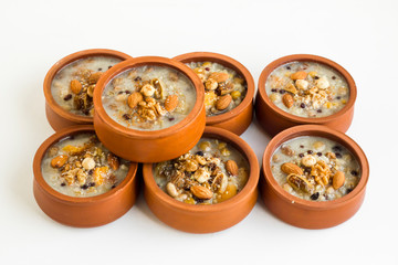 Traditional Turkish Dessert Asure,Ashura or Noah's Pudding in ceramic casserole bowls on white surface.