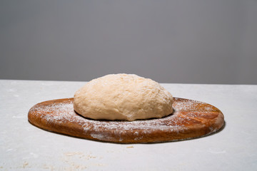 a dough for pizza on white table on wooden Board