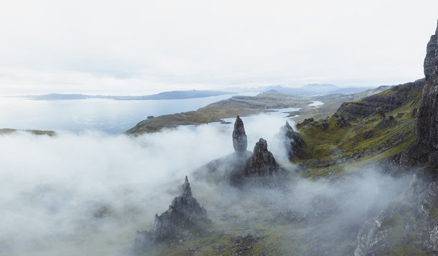 Luftaufnahme von Old Man of Storr Schottland in gr&uuml;ner H&uuml;gellandschaft umh&uuml;lt mit Nebel und See im Hintergrund. 
