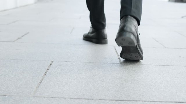 Businessman feet walking on urban street. Employee in black shoes going for work