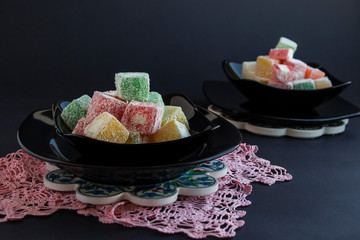 Traditional Turkish delight designed in black color glass plates on black surface.The Sugar Feast concept.