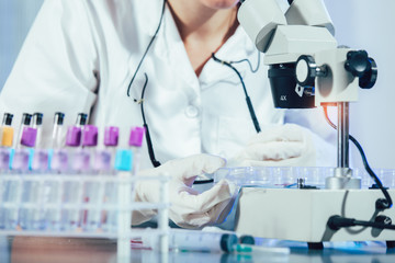 Fototapeta premium Lab technician assistant analyzing a blood sample in test tube at laboratory. Medical, pharmaceutical and scientific research and development concept.