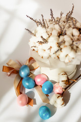 Easter card with dyed eggs and cotton flowers on a white background. Beautiful easter composition. Easter egg hunt.