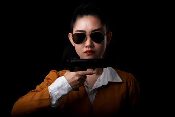 Portrait beautiful asia woman wearing a yellow suit one hand holding pistol gun at the black background, Young sexy girl long hair with a handgun look at the camera, Pretty women stand with a guns