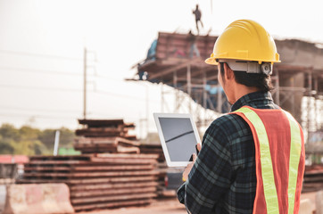 Construction engineers are using tablets to inspect construction projects on the background of the...