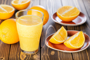 Healthy morning drink. Orange juice glass and fruits on wooden table.