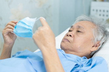 Asian senior or elderly old lady woman patient wearing a face mask in hospital for protect infection and kill Novel Coronavirus (2019-nCoV) Covid-19 virus.