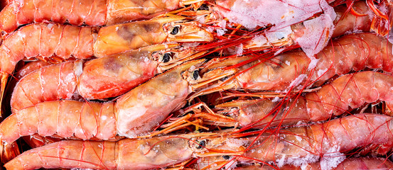 Amazing fresh large frozen shrimps. Pink fresh uncooked shrimps. Close-up. Delivery of frozen seafood to stores in package with hoarfrost. Delicacies, sea food concept. Top view.