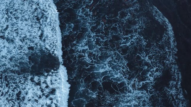 Top down aerial view of giant dark blue sea waves crashing and foaming at the beach. The reef is making powerful wave on a sunny day and amazing landscape.