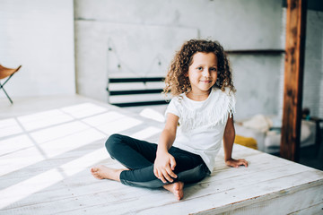 Smiling girl sitting with crossed legs in loft room
