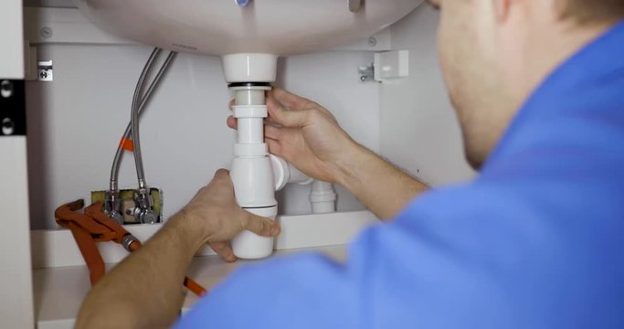 plumber installing sink siphon in domestic bathroom