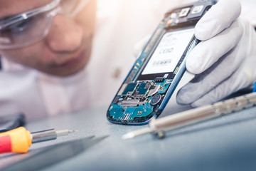 The asian technician repairing the smartphone's motherboard in the lab with copy space. the concept...