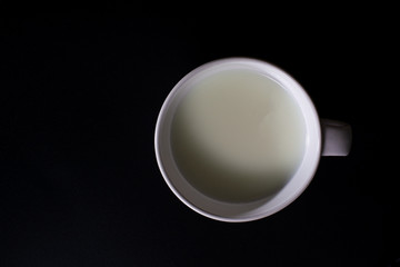 Top view of white cup of milk on black background with copy space. High protein and calcium. Healty beverage.