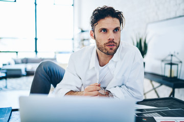 Fototapeta premium Concerned businessman working on project in apartment