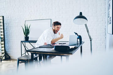 Cheerful freelancer celebrating success of project at workplace