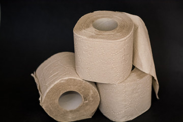 On black background, three piles of grey open toilet paper.