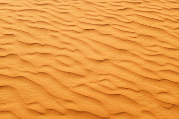 Fototapeta na wymiar Rich orange color desert sand wave patterns for a warm summer background.
