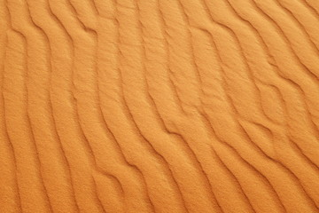 Fototapeta na wymiar Bright orange desert sand ripples for a hot summer background.