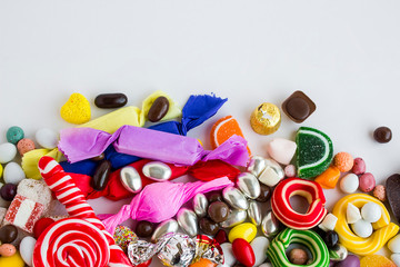 Colorful candies and dark chocolate balls on white background with copy space.