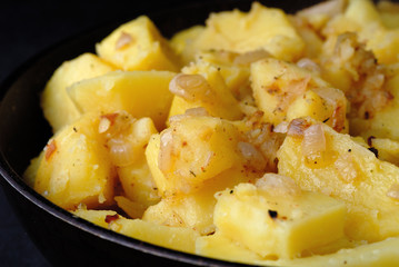 Freshly fried potatoes with onions in a pan closeup. Shallow depth of field