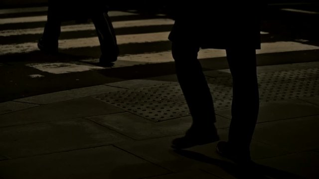 Close up of people walking across Zebra Crossing at night