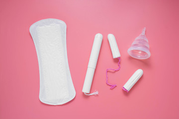 Woman hygiene products, menstruation, cotton tampons, sanitary pads, menstrual cup for woman critical days. Pink background with copy space.