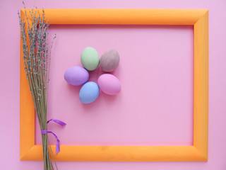 Flat lay composition of Happy Easter holiday concept. Colorful pastel egg with lavender flower in orange frame on pink background. Space for design, top view.