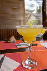 Margarita cocktail with ice cubes and lemon slice and salt. Cold cocktail in martini glass. Alcoholic drinks concept. Glass of Margarita cocktail on the bar. Juicy tropical cocktail. Bar and drinks. 